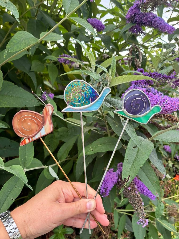 Colourful stained glass snail plant stakes standing in a pot